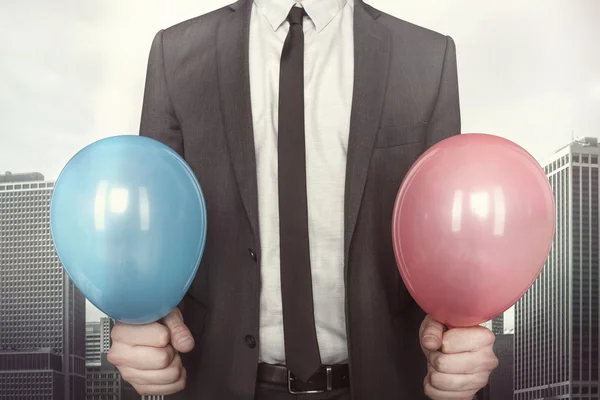 Homme d'affaires tenant des ballons dans les mains sur fond de paysage urbain — Photo