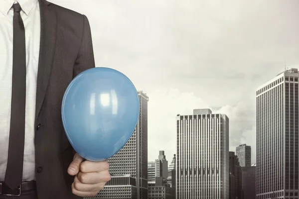 Geschäftsmann hält Luftballon in der Hand auf Stadtbild Hintergrund — Stockfoto