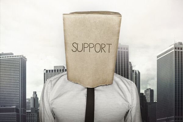 Support text on brown paper bag which businessman has on head
