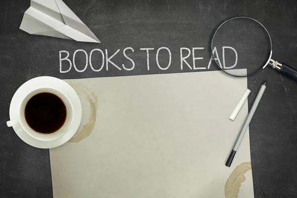 Bücher zum Lesen auf schwarzer Tafel mit leerem Blatt Papier — Stockfoto