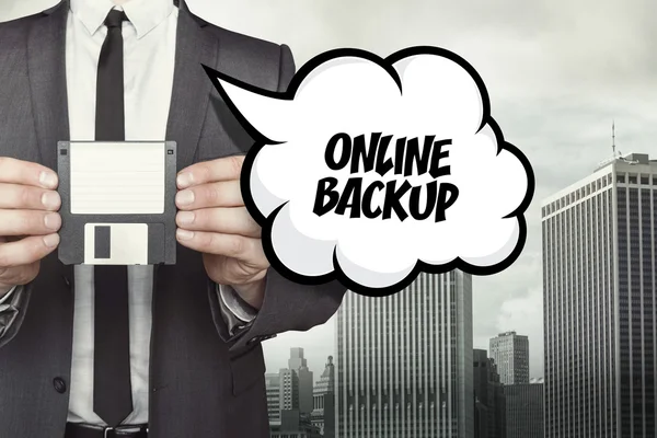 Online backup text on speech bubble with businessman holding diskette — Stock Photo, Image