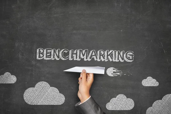 Benchmarking concept on blackboard with paper plane — Stock Photo, Image