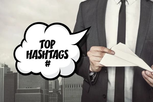 Top hashtags szöveg beszéd buborék, üzletember, tartja a kezében a papír sík — Stock Fotó