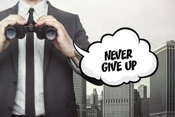 Never give up text on speech bubble with businessman holding binoculars — Stock Photo, Image