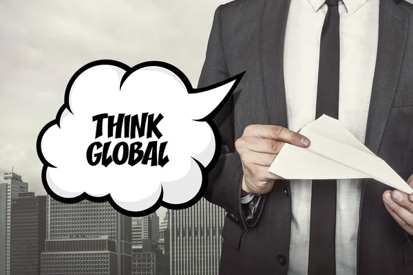 Denk dat globale tekst op de tekstballon met zakenman papier vliegtuig in de hand houden — Stockfoto