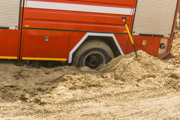 Schop vast te zitten naast een brandweerwagen begraven wiel. — Stockfoto