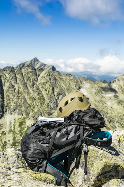 Guide book, a helmet and a backpack with peaks in the background. — Stock Photo, Image