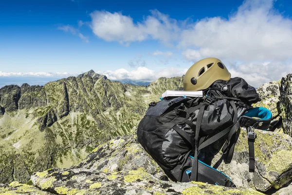 Guida, casco kaki scuro e zaino nero in montagna . — Foto Stock