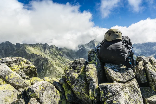 Zaino nero con casco sulla cima di una montagna . — Foto Stock