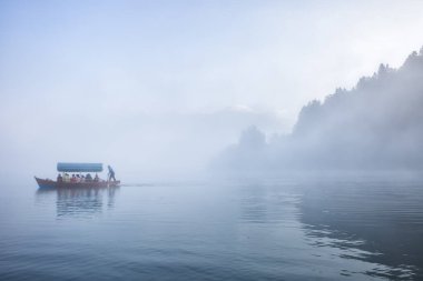 Bled Gölü 'nde sis, Slovenya' da turist dolu bir tekne..