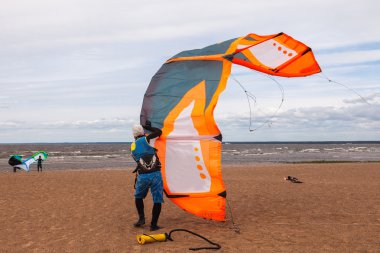 Kite surfer wearing a wetsuit is preparing his kite on a windy d