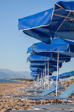 Güneş şemsiyesi ve Sahilde şezlong