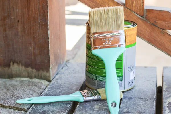 jar  of  paint  next  to  two  brushes  to paint  a  ladder