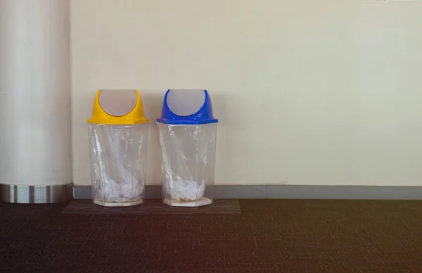 Clear plastic dustbin On the floor, gray carpet and gray walls