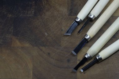 Koyu kahverengi ahşap arka planda ahşap oyma bıçağı kullanıldığına dair izler var.