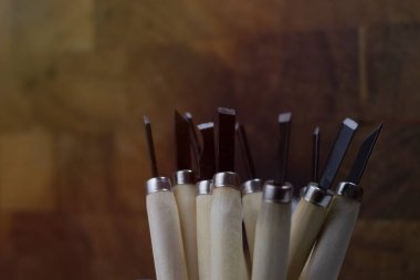 Bulanık, ahşap saplı oyma bıçağı koyu kahverengi ahşap arka planda kullanım izleri var.