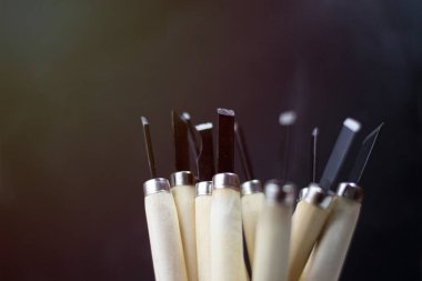 Bulanık, tahta saplı, oyma bıçaklı. Karanlık bir arka planda.