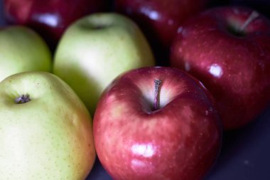 Birkaç parlak kırmızı ve yeşil elma sıraya dizildi