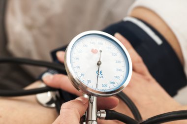 Erkek doktor bir tansiyon aleti kullanır