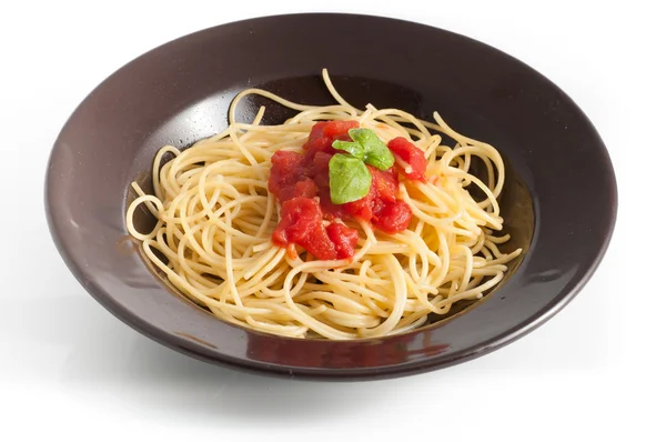 Spaghetti con pomodoro fresco e basilico serviti su piatto scuro — Foto Stock