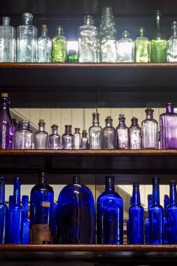 Childers, Queensland, Avustralya 'daki eski eczanede sergilenen renkli cam ilaç şişeleri..