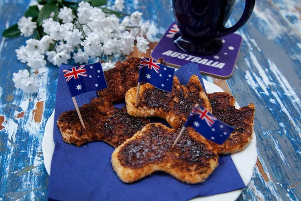 A plate of toast with vegemite, the iconic Australian savoury spread, cut into the shape of Australia as a special breakfast for Australia Day, 26th January.