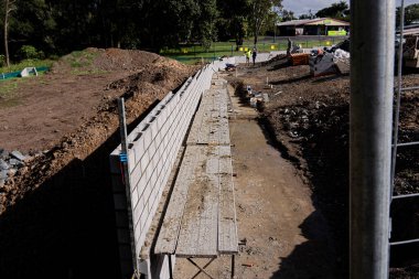 İşçiler Avustralya, Queensland 'da yoğun bir çalılığın yanına beton tuğla duvar örüyor..