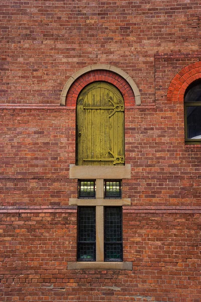 Old commercial brick building with a high level yellow loading door on a laneway in Brisbane, Queensland, Australia.