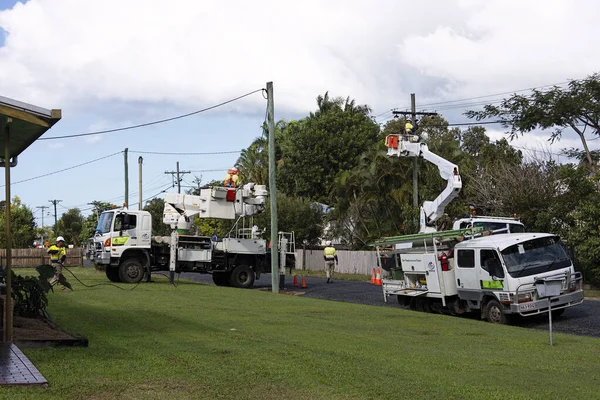 Walkerston, Queensland, Avustralya - 9 Temmuz 21 Temmuz, elektrik işçisi bir kova kamyonunda elektrik direği üzerinde çalışıyor ve arkasında bulutlu bir gökyüzü ve tropikal bitki örtüsü ile yeni kablolar asıyor..