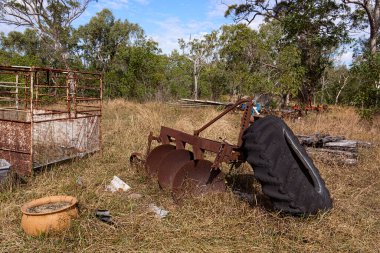 Queensland kırsalındaki bir otlakta terk edilmiş saban ve sığır sandığı da dahil olmak üzere eski tarım makineleri..
