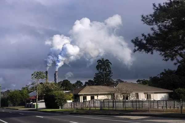 北クイーンズランドのマリアンヌにある製糖工場と工場から煙が立ち上がり 曇り空に対する砂糖破砕期に小さな町の上に煙が吹きました — ストック写真