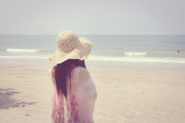 Genç kadın tropik sahilde denize bakarak dinlenmek