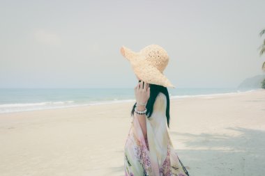 Genç kadın tropik sahilde denize bakarak dinlenmek