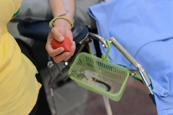 Донор крови мужчина с резиновым мячом в руке, сдача крови — стоковое фото