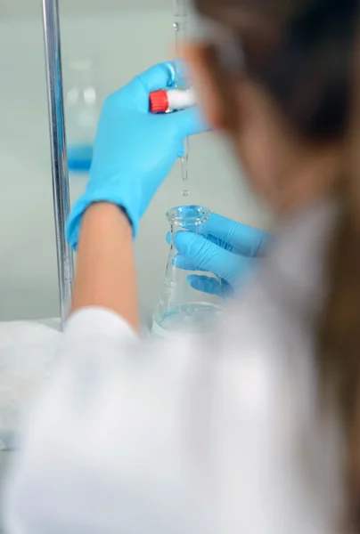 A mulher que é a cientista demonstra a técnica de titulação. — Fotografia de Stock