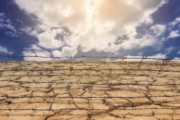 Ostnatý drát plotu s sucha pozemky pod širým nebem — Stock fotografie