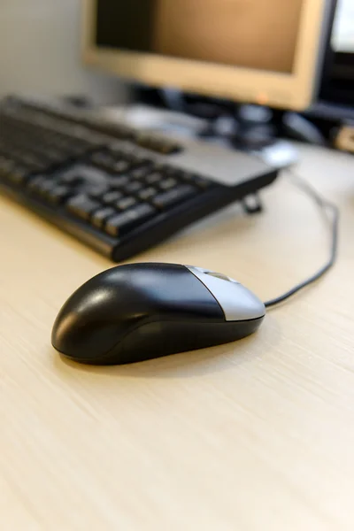 Closeup computer mouse before computer desktop on brown wooden d