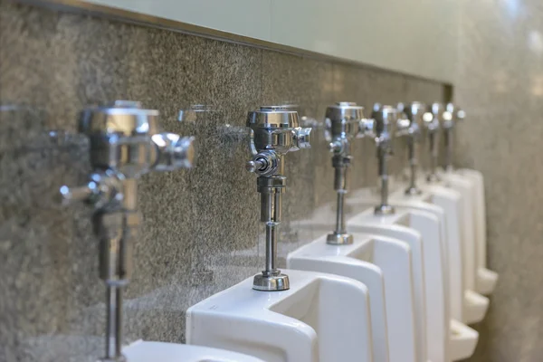 Línea de urinarios blancos claros en baños públicos hombre, interior de t —  Fotos de Stock