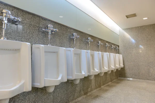 Line of clear white urinals in public toilets man, interior of t Stock Image