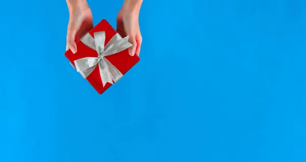 Weibliche Hände Halten Geschenkverpackung Rotem Papier Mit Schleife Auf Blauem — Stockfoto