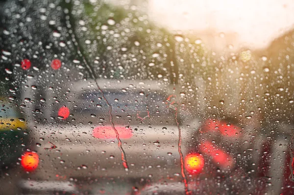 Raindrops run down on car windshield from inside view. Traffic jam during the heavy rain storm