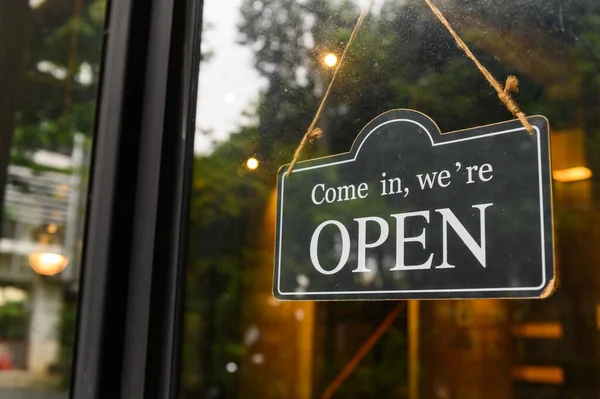 COME IN, WE ARE OPEN - Open sign broad hang on entrance door with copy space at coffee shop or restaurant