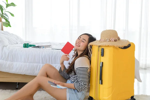 Genç Asyalı bir kadının portresi ve elinde sarı bavul ve şapkalı bir pasaport var. Yaz zamanı seyahat etme zamanıdır..