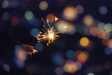 Bokeh arka planında maytap tutan kadın eller. Kutlama için yanan maytap, festival partisi geçmişi.