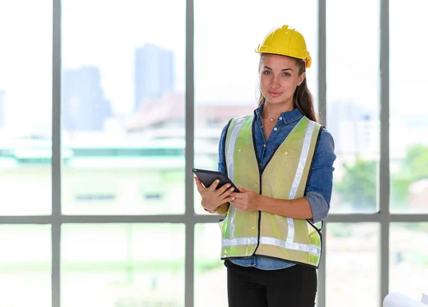 Portrait of female construction engineer workers in yellow hardhat with a tablet computer in construction site