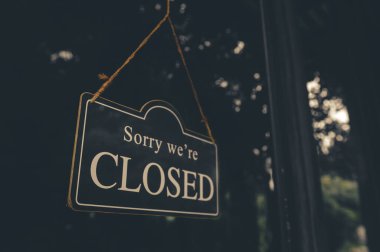 SORRY WE ARE CLOSED - Close sign broad hanging front of entrance door with copy space at coffee shop or restaurant clipart