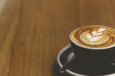 Kafe 'de üzerinde güzel latte sanat eserleri olan bir fincan taze kahve ve fotokopi alanı. Kahve molası rahatlama