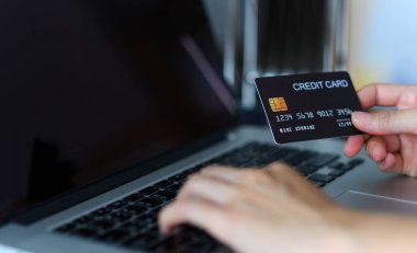 Kredi kartı tutan ve internetten bilgisayar alışverişi yapan kadınların ellerini kapat. E-ticaret, internet bankacılığı, kontrol bakiyesi, bankacılık hizmeti, kredi kartıyla ödeme, ödeme