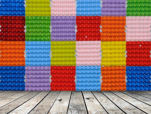 Bandeja de ovo de papel colorido com piso de madeira, fundo colorido — Fotografia de Stock
