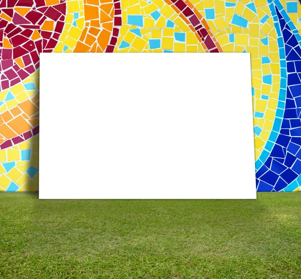 Cartaz em branco com parede de mosaico colorido e gramado verde para mensagem de informação — Fotografia de Stock